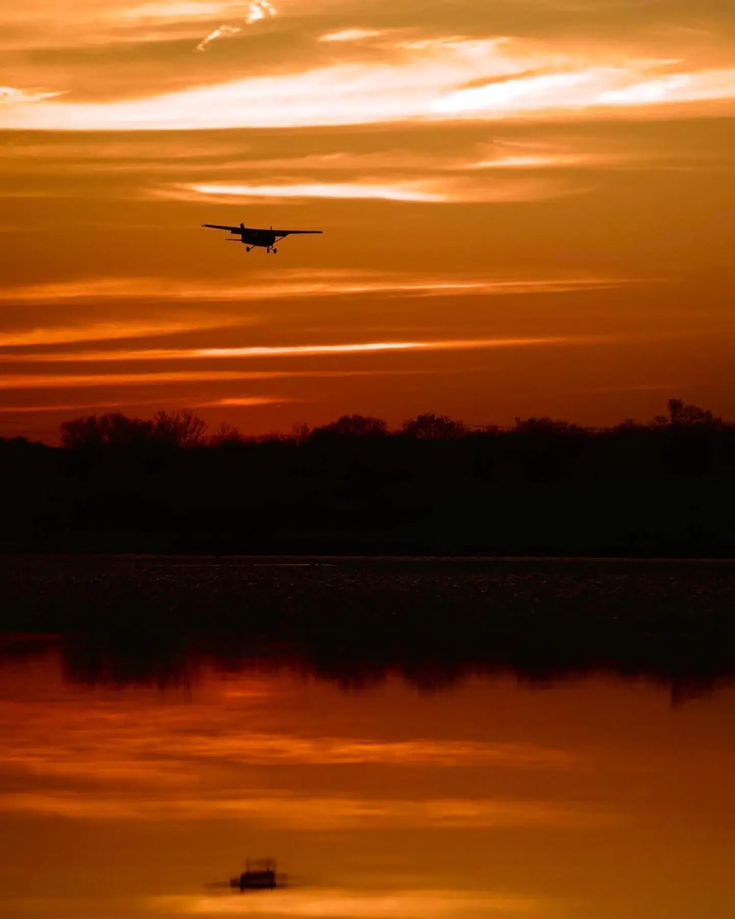 Airplane flying over water at sunset during Dayton Aviation Services flight training