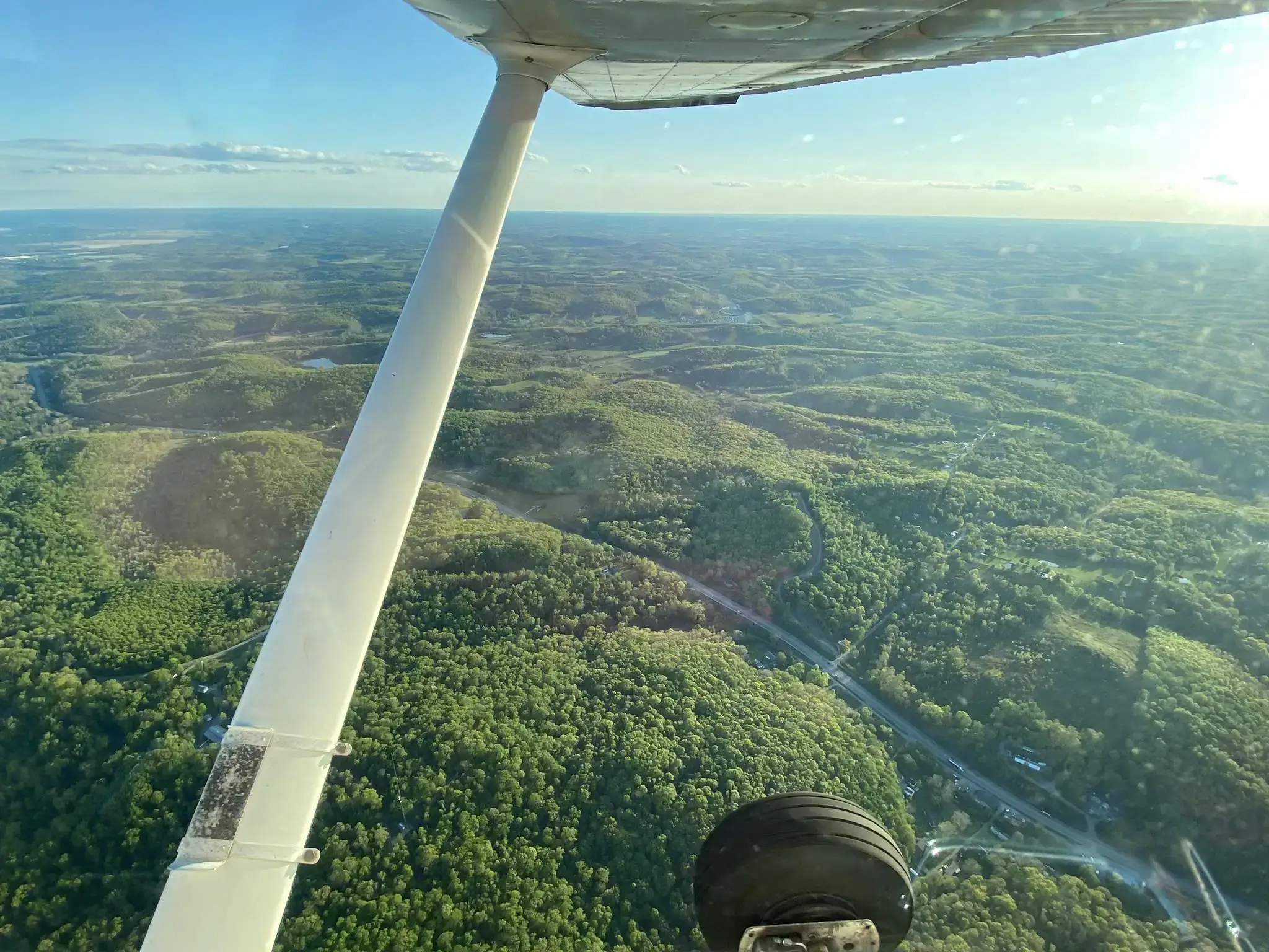 Woman pilot flying plane in bright daylight seen from the side of the cockpit